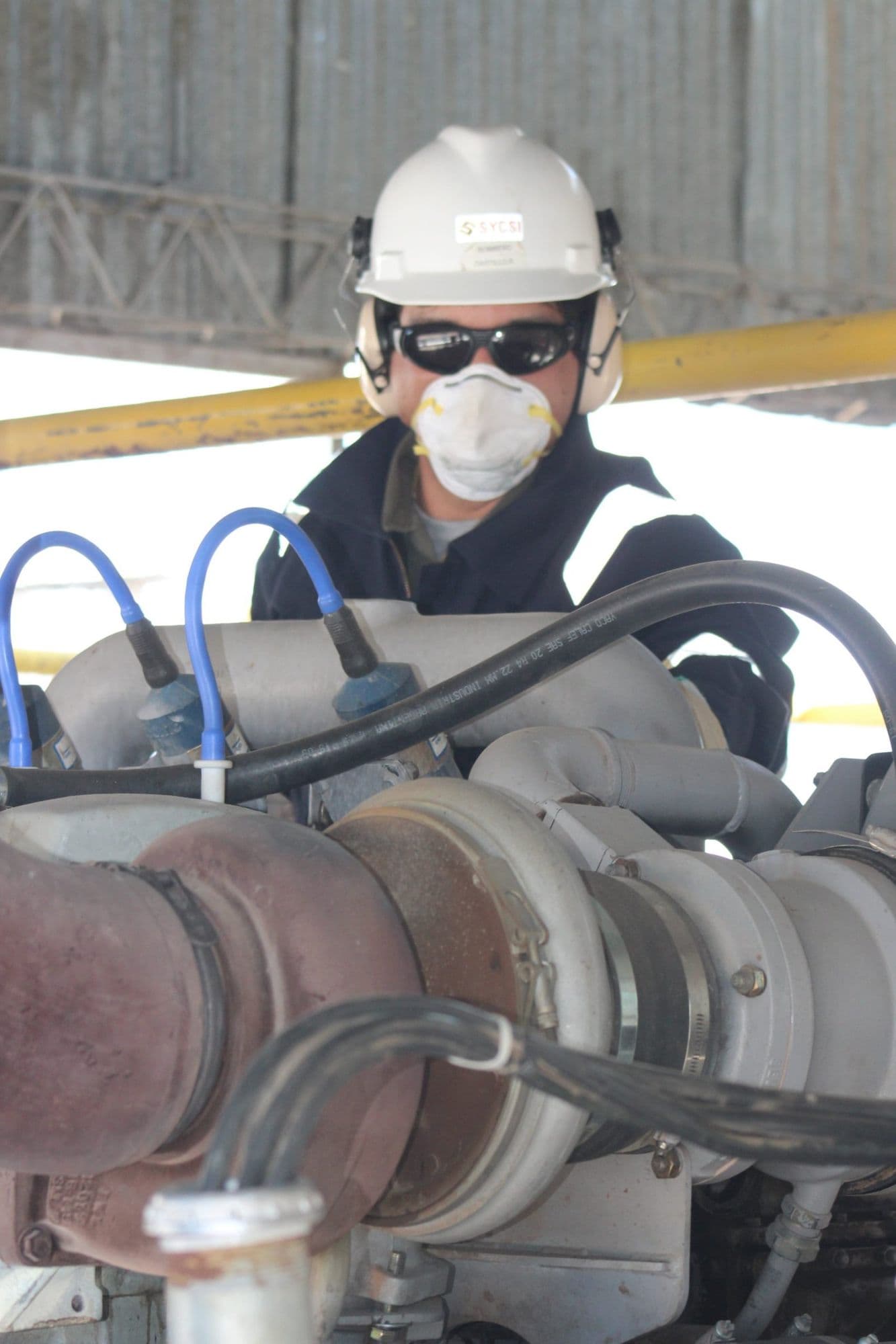 Técnico de SIELC con EPP trabajando sobre un compresor